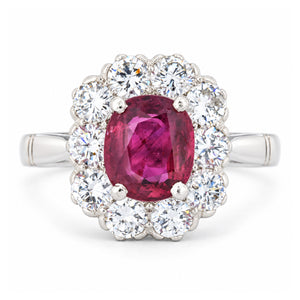 Front view of a vintage 1960s engagement ring featuring a vibrant oval ruby encircled by brilliant-cut diamonds in polished white gold.