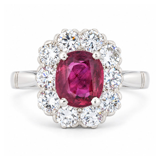 Front view of a vintage 1960s engagement ring featuring a vibrant oval ruby encircled by brilliant-cut diamonds in polished white gold.
