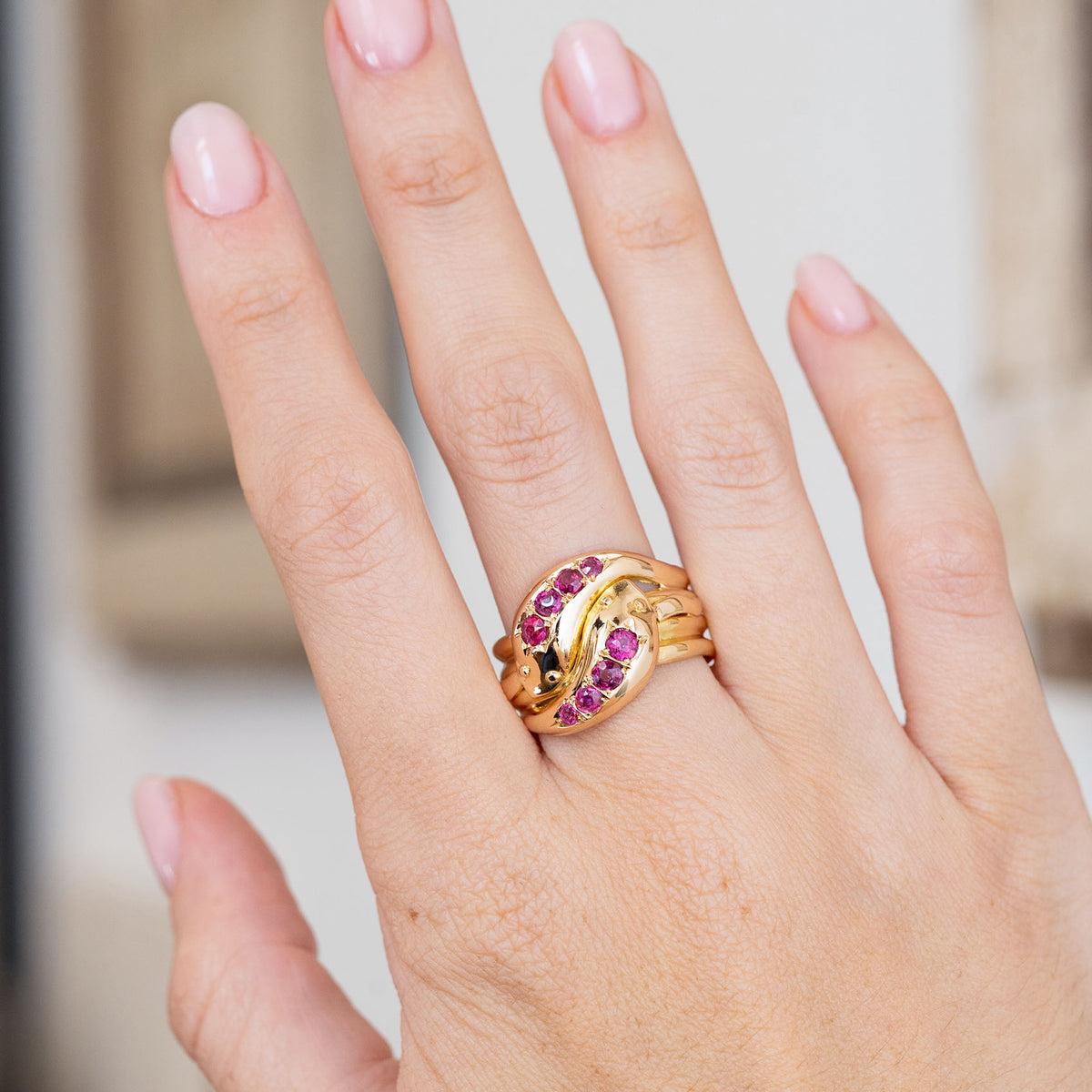 Victorian ruby snake ring worn on the hand, showcasing its bold intertwined yellow gold form.