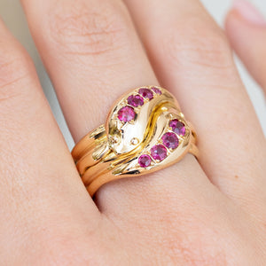 Close-up of the vintage Victorian ring worn on the finger, with two ruby-set snake heads crossing in yellow gold.