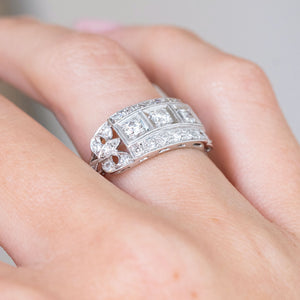 Side-angled view of the antique Art Deco ring, showing its sculptural diamond-set shoulders and raised platinum setting.