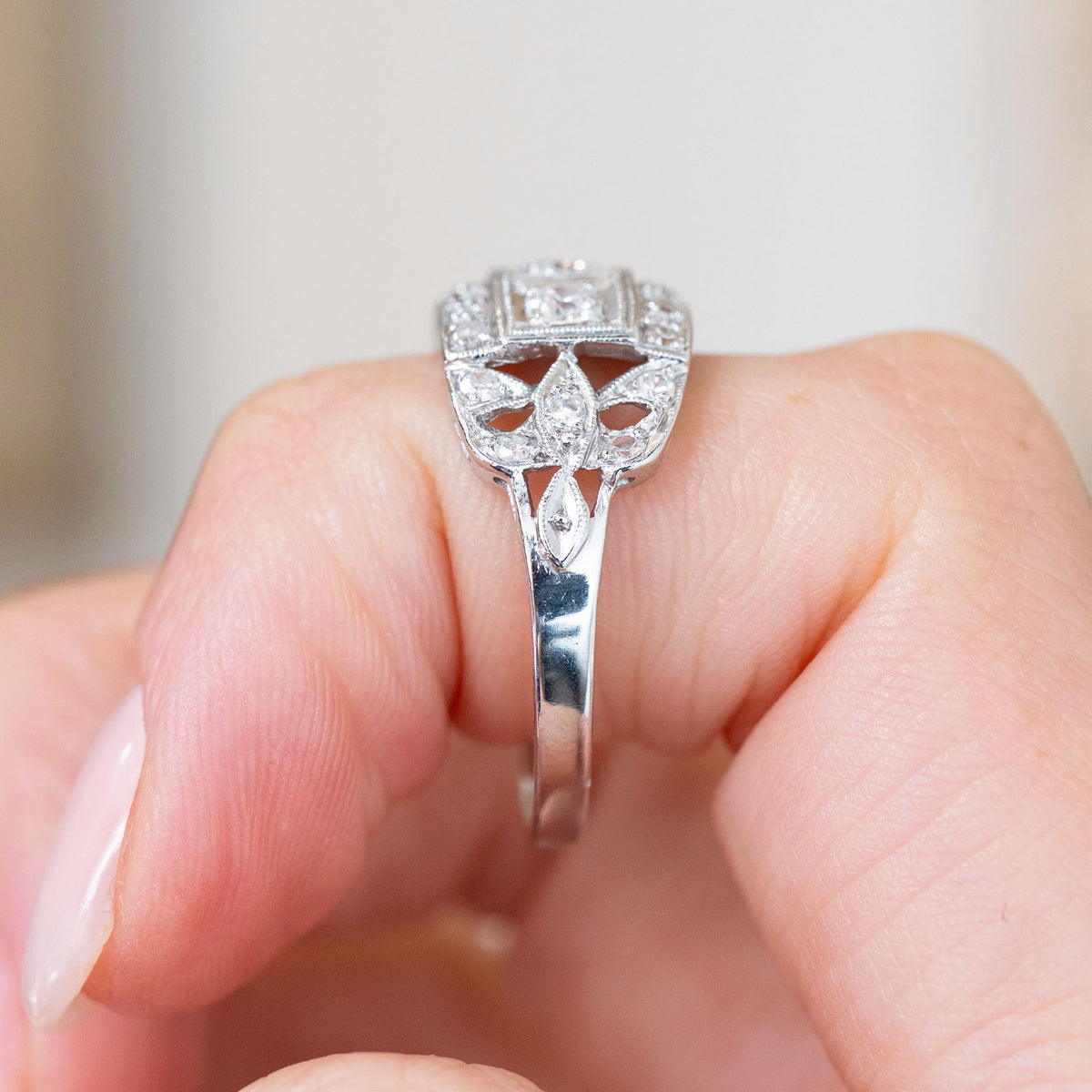 Profile detail of the platinum engagement ring, featuring openwork construction beneath the vintage diamond cluster.