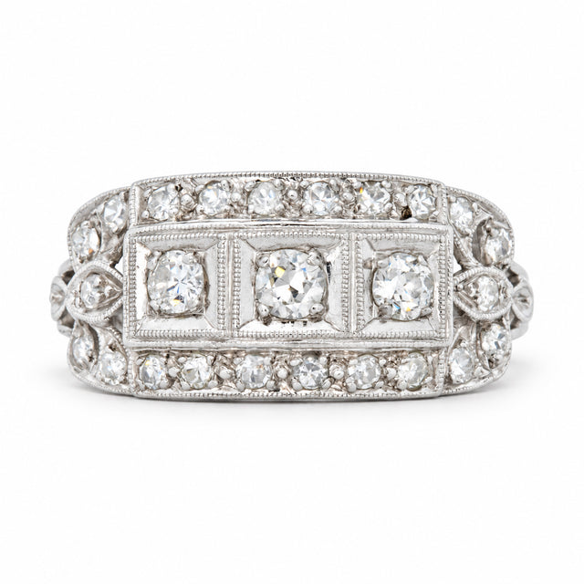 Antique Art Deco diamond cluster engagement ring in platinum, with three central diamonds framed by an intricate geometric diamond design.