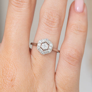 Close-up on-hand view of the white gold and platinum ring, featuring a central diamond within a hexagonal diamond surround.