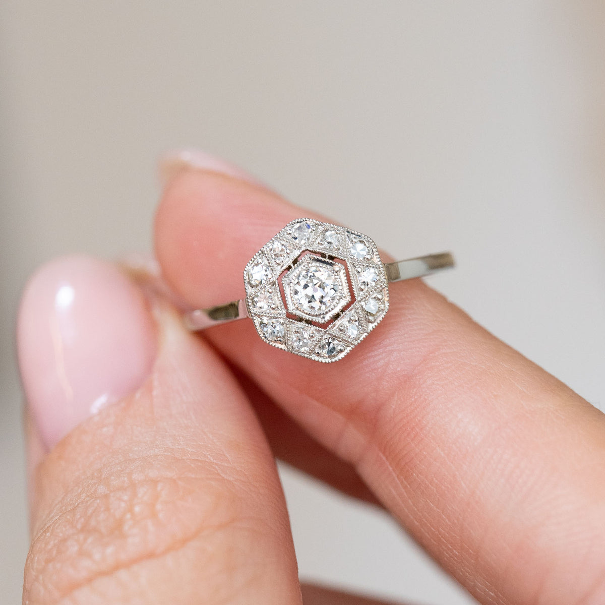 Art Deco diamond ring held between the fingers, offering a detailed look at its old-cut and single-cut stones.