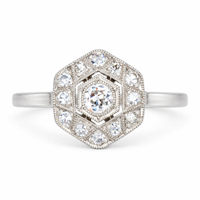 Antique Art Deco diamond cluster engagement ring in white gold and platinum, set with old-cut and single-cut diamonds in a geometric hexagonal design.