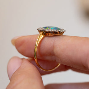 Profile view of the antique cluster ring, displaying the low-set oval opal, platinum gallery and polished yellow gold shank.