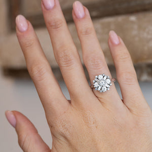 Vintage white gold diamond cluster engagement ring worn on a hand, showcasing its bold proportions and floral-inspired setting.