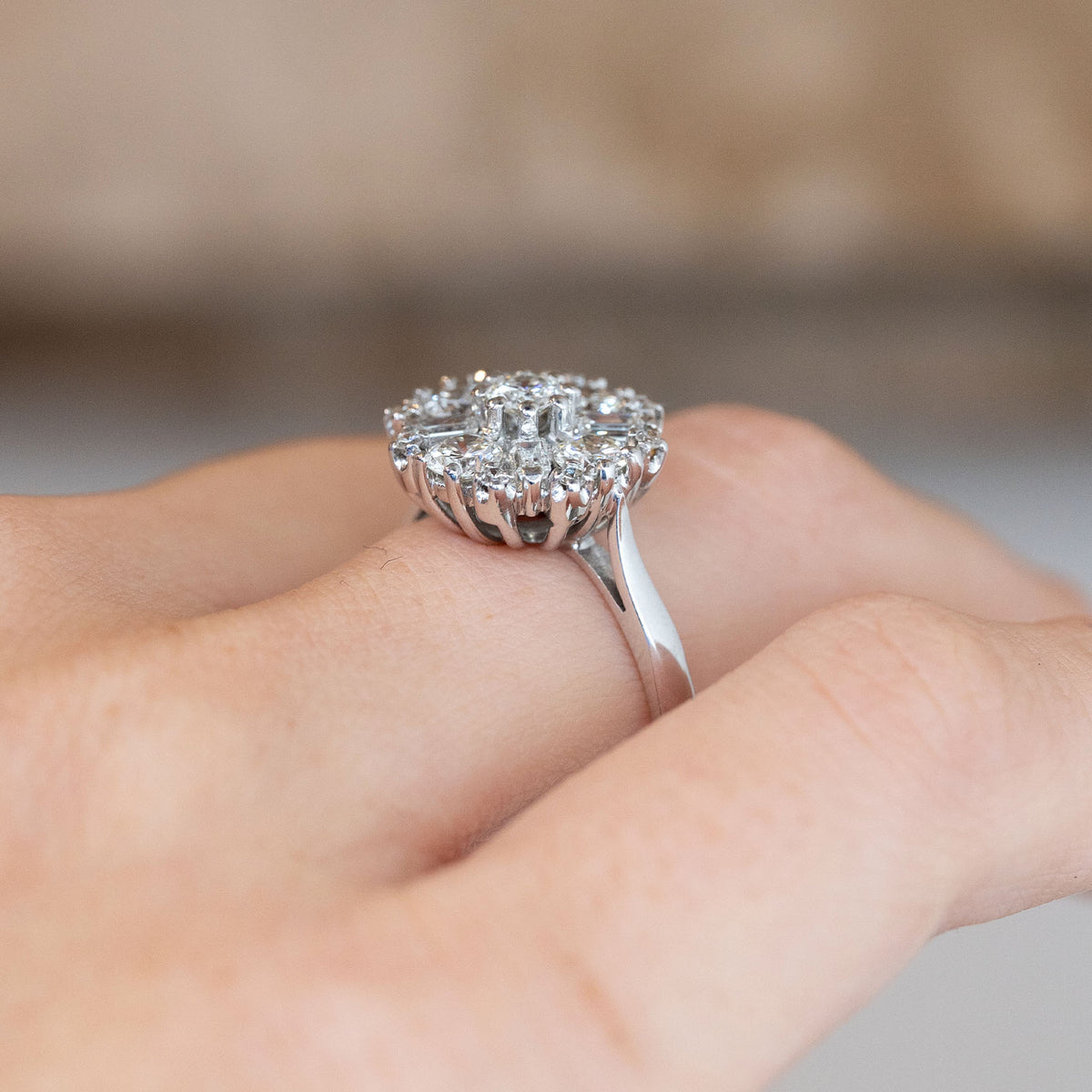 Side-angle view of the diamond cluster ring worn on a hand, highlighting the elevated setting and polished white gold band.