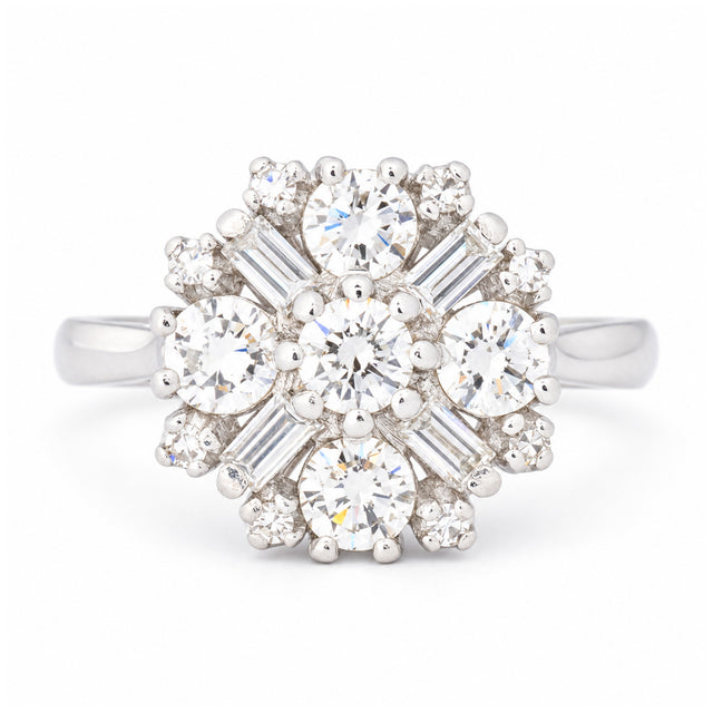 Vintage 1980s diamond cluster engagement ring in white gold, featuring round brilliant-cut and baguette-cut diamonds in a floral-inspired design.