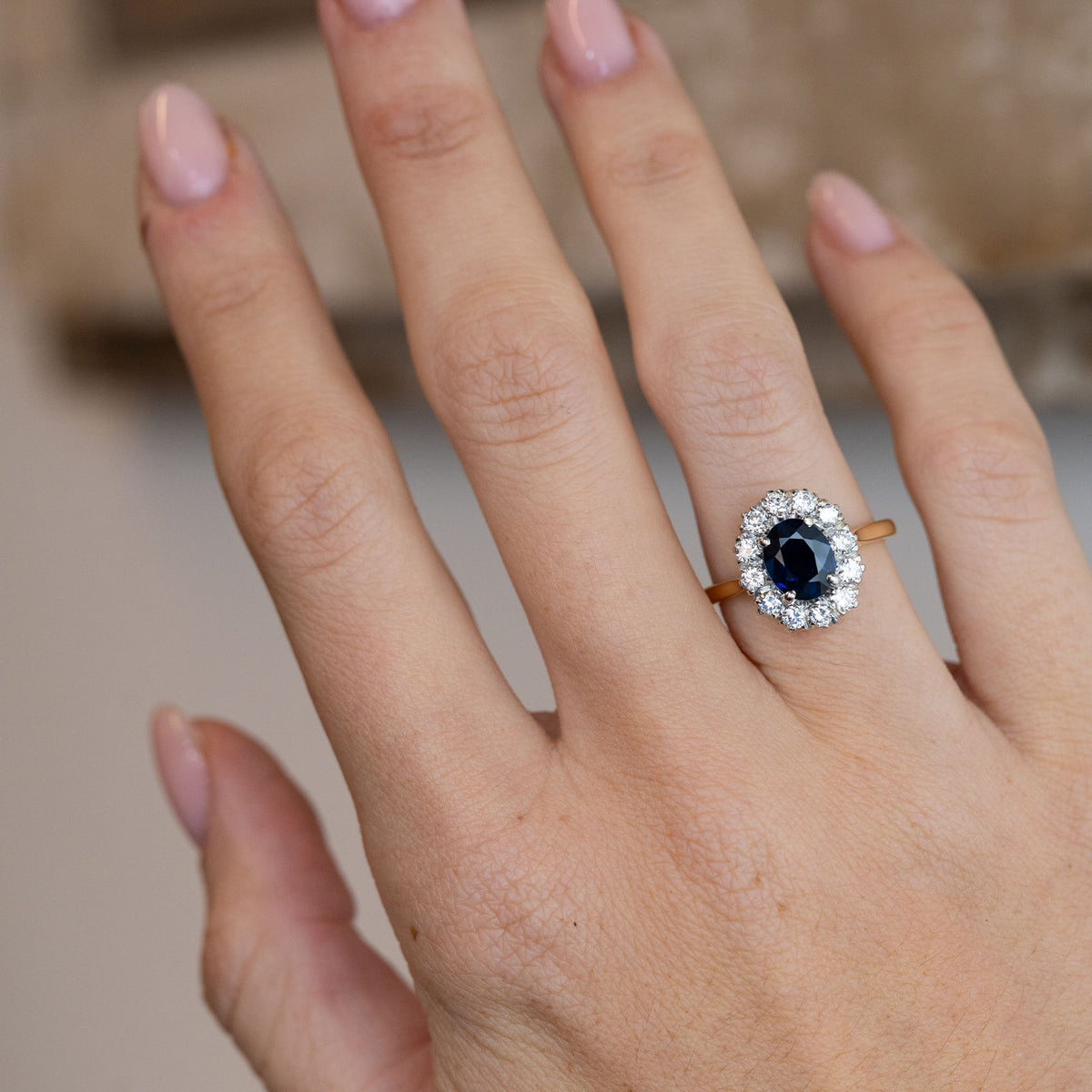 Dark blue sapphire and diamond engagement ring worn on a hand, showcasing its elegant proportions and classic 1940s cluster design.
