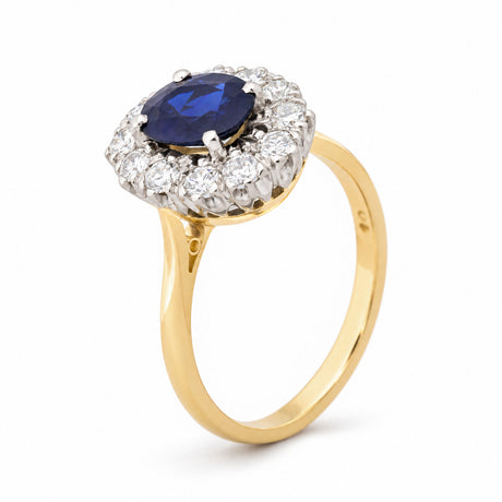 Angled view of the vintage sapphire cluster ring, highlighting the raised platinum setting and polished yellow gold band.