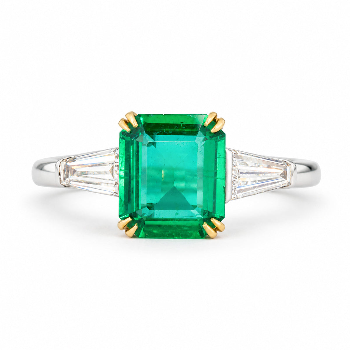 Vintage emerald and diamond three-stone engagement ring, featuring an emerald-cut centre stone flanked by two trapezoid diamonds on a white gold band.