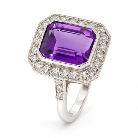 Angled view of an antique Art Deco amethyst and diamond cluster ring in white gold, showcasing its vibrant purple amethyst, octagonal diamond surround and diamond-set shoulders.