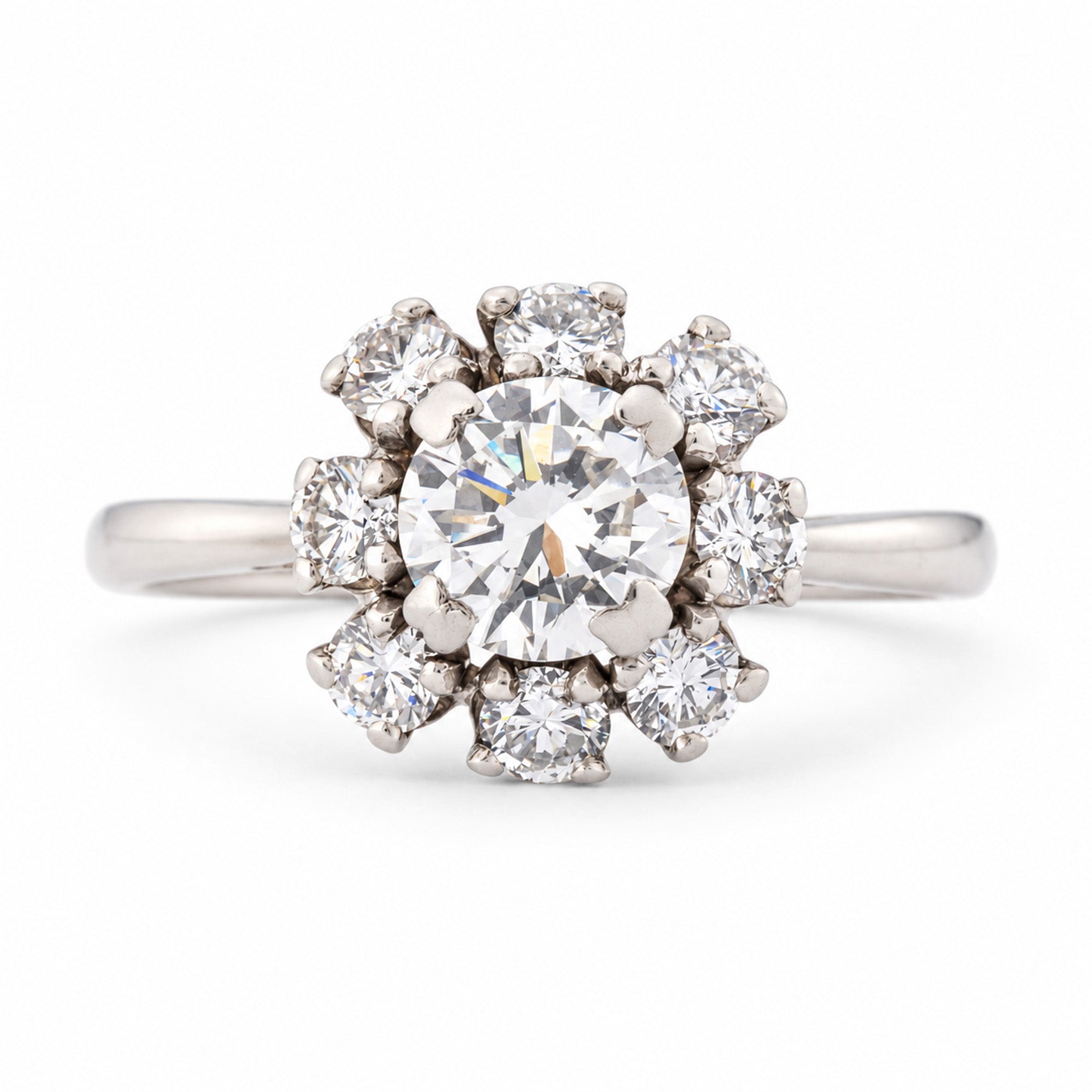 Front view of a vintage 1950s diamond cluster engagement ring in white gold, featuring a central round brilliant-cut diamond surrounded by eight smaller diamonds in a floral cluster setting.
