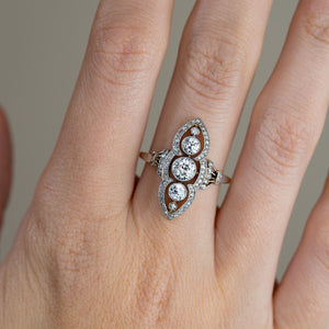 Close-up of the Art Nouveau ring on a finger, showcasing the graduated diamonds framed by a delicate platinum border.