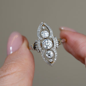 Detailed close-up of the Art Nouveau diamond ring held between fingers, highlighting its elongated marquise-shaped outline and symmetrical diamond arrangement.