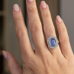Antique blue sapphire and diamond cluster ring worn on the hand, showing the impressive proportions of its oval Victorian design.