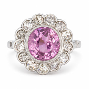 Vintage 1960s pink sapphire and diamond cluster engagement ring in white gold and platinum, with a large pink centre stone and diamond halo.