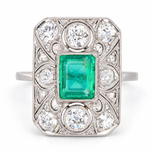 Antique Art Deco Colombian emerald and diamond panel cluster ring in platinum, featuring a rub-over set emerald, old-cut diamonds and intricate filigree lacework.