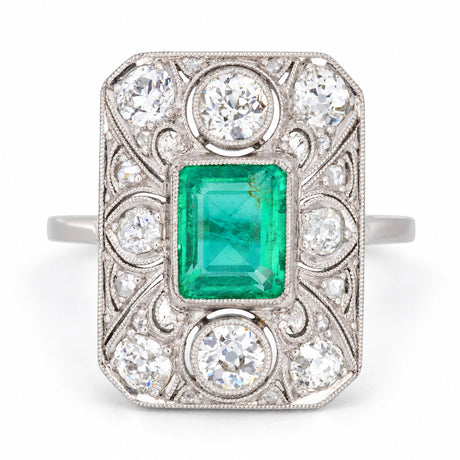 Antique Art Deco Colombian emerald and diamond panel cluster ring in platinum, featuring a rub-over set emerald, old-cut diamonds and intricate filigree lacework.