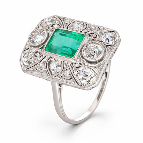 Three-quarter studio view of the antique platinum ring, showcasing its rectangular panel, vivid Colombian emerald and openwork diamond setting.