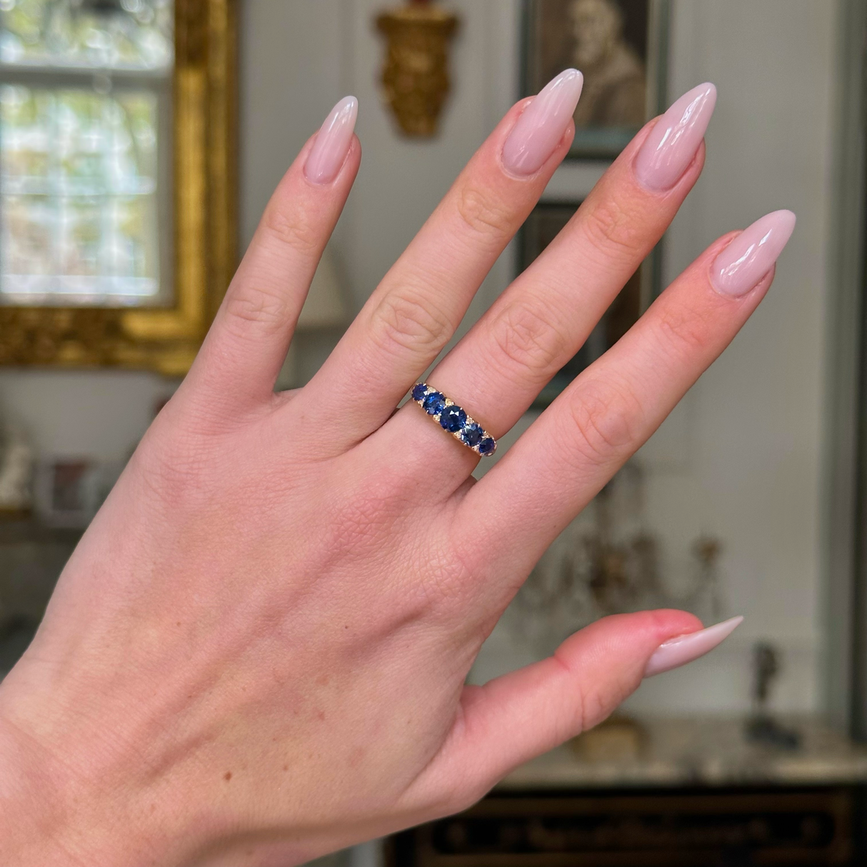 sapphire and diamond five stone ring on hand. 