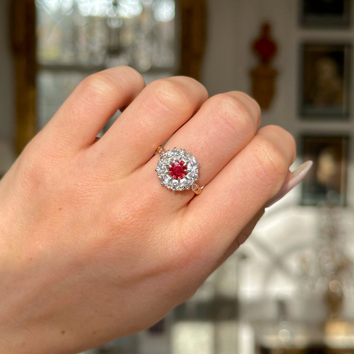 Antique victorian ruby and diamond cluster engagement ring worn on closed hand. 