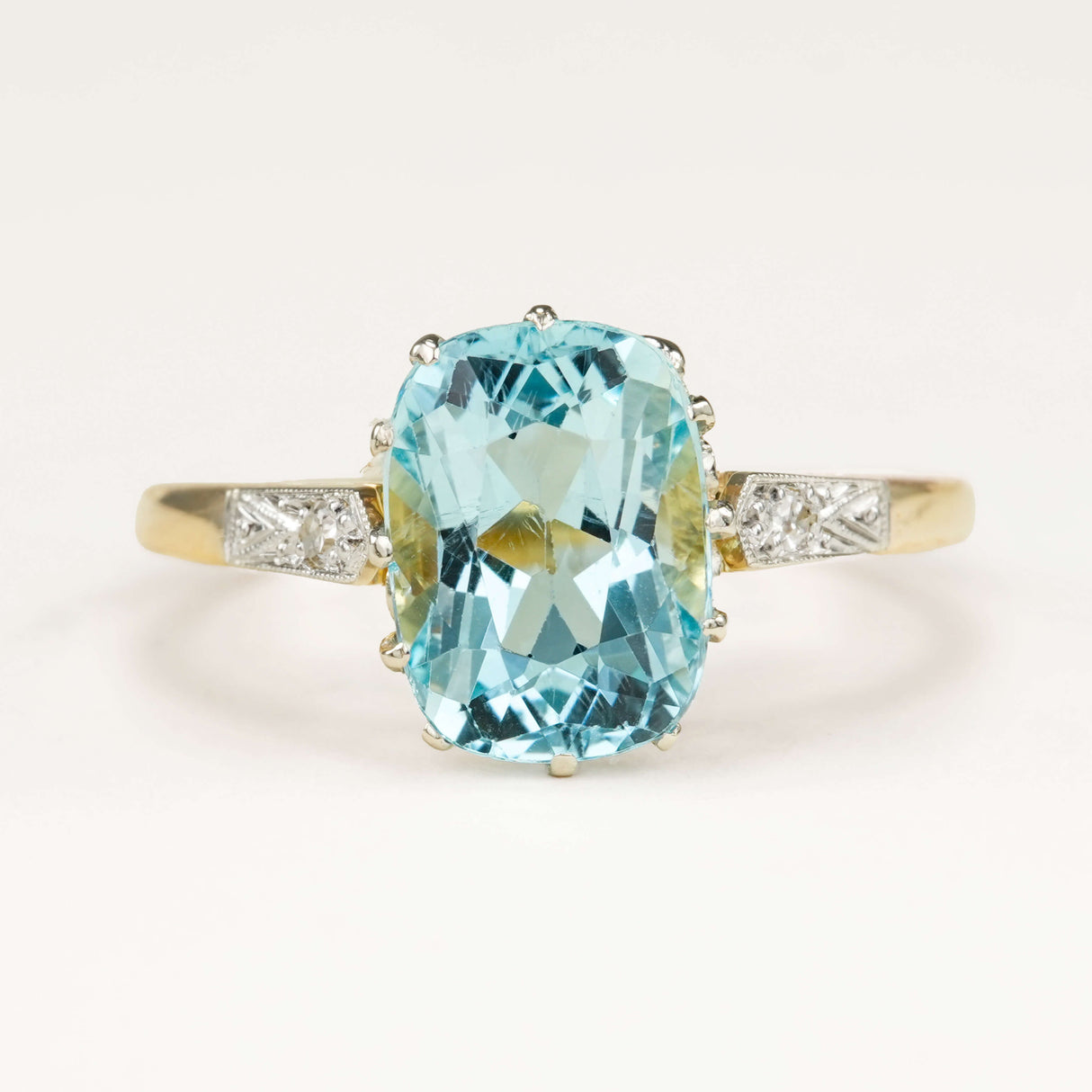 Antique Edwardian engagement ring set with a cushion-cut aquamarine and surrounding diamonds, showcasing delicate period craftsmanship and soft blue colour.