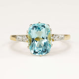 Antique Edwardian engagement ring set with a cushion-cut aquamarine and surrounding diamonds, showcasing delicate period craftsmanship and soft blue colour.
