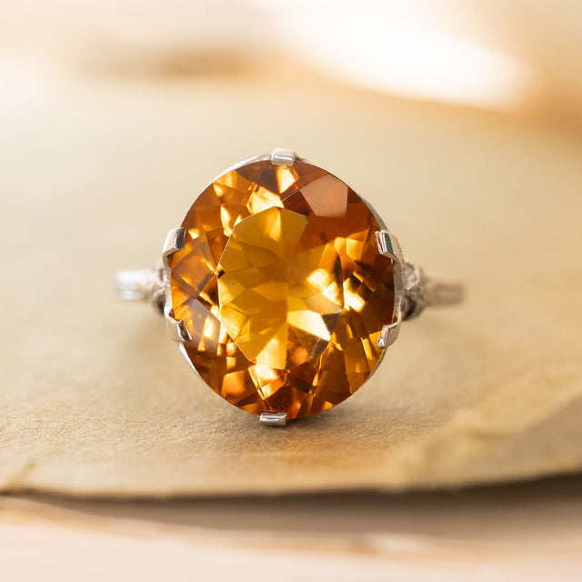 An Antique Art Deco citrine cocktail ring set in platinum displayed on an old book cover.
