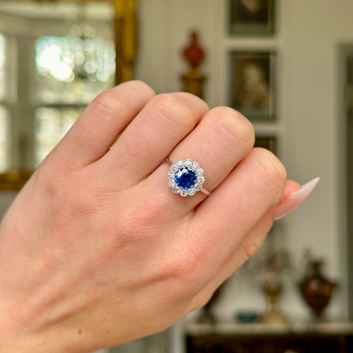 Antique sapphire and diamond cluster ring, worn on  closed hand. 