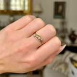 Antique four-stone diamond ring worn on closed hand.