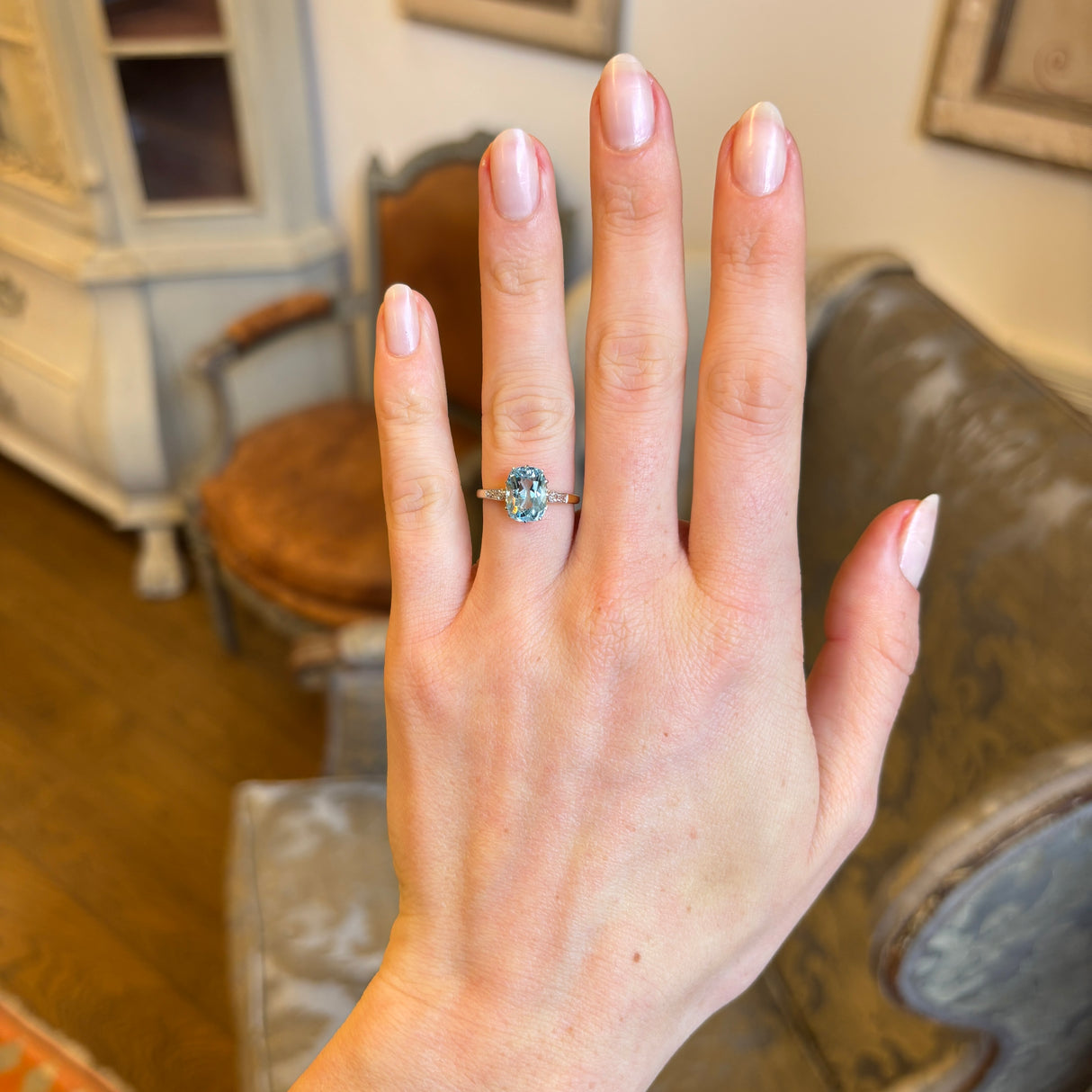 Antique Edwardian cushion-cut aquamarine and diamond engagement ring worn on the hand, providing a sense of size and proportion.