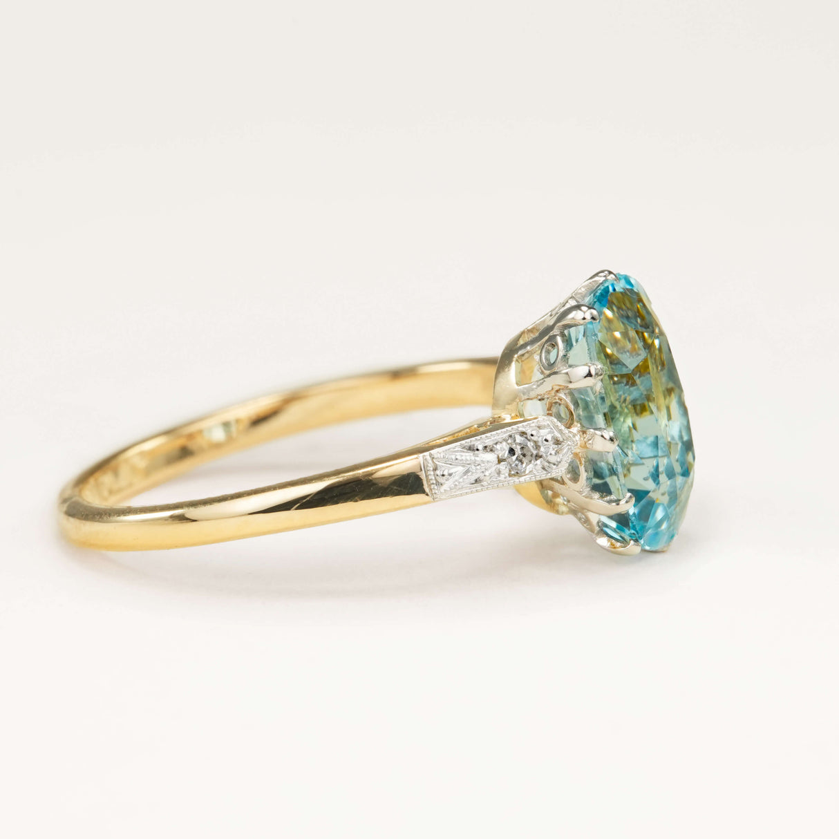 Antique Edwardian cushion-cut aquamarine and diamond engagement ring resting on a neutral surface, showing the aquamarine centre and diamond accents.
