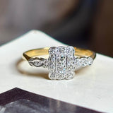Antique, Edwardian diamond panel cluster engagement ring placed on vintage book with blurred background
