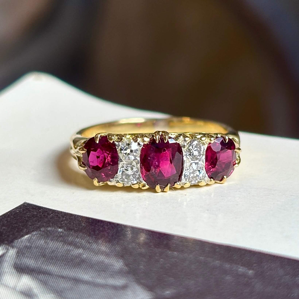 Antique, Victorian ruby and diamond three-stone ring placed on vintage book 