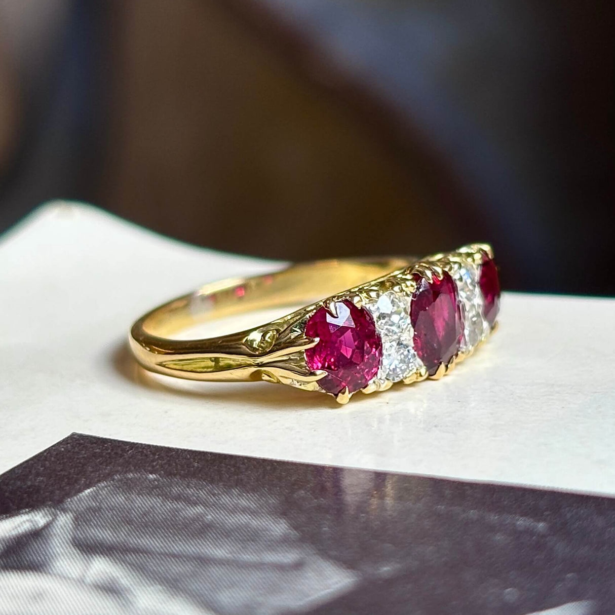 Antique, Victorian ruby and diamond three-stone ring on vintage book side view