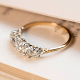 A Victorian five-stone old-mine cut diamond engagement ring set in silver with an 18ct yellow gold band displayed on book pages. 