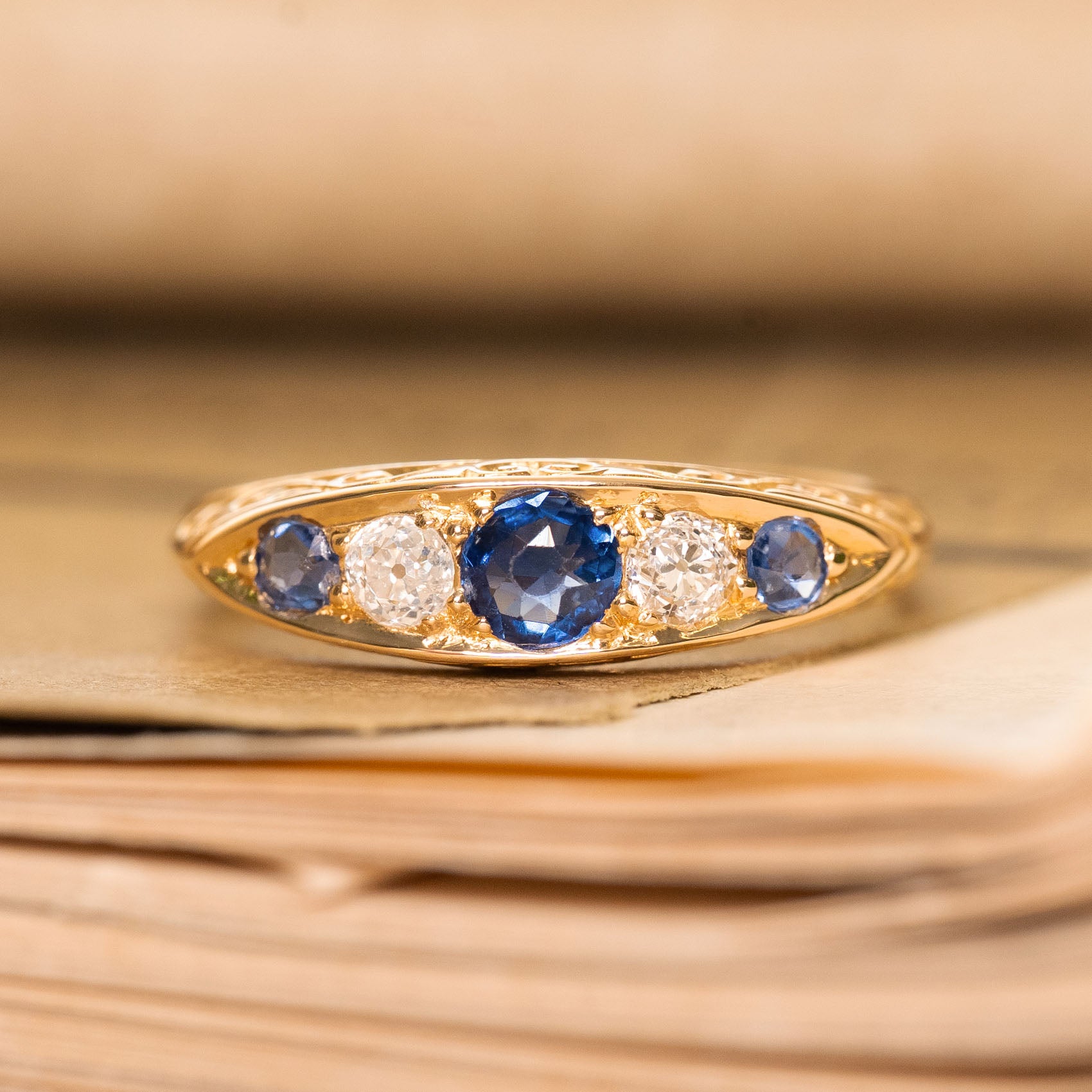 An antique gold ring with three blue sapphires and two diamonds from the Victorian era. 