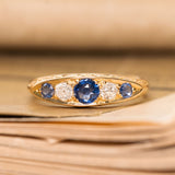An antique gold ring with three blue sapphires and two diamonds from the Victorian era. 