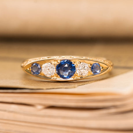 An antique gold ring with three blue sapphires and two diamonds from the Victorian era. 