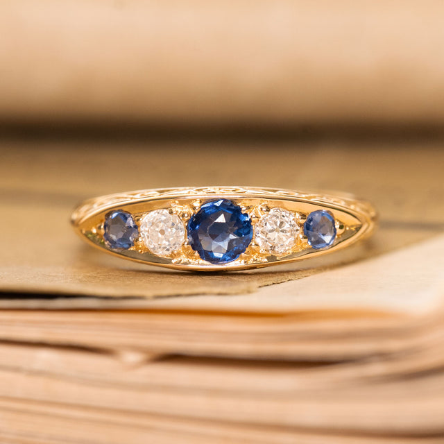An antique gold ring with three blue sapphires and two diamonds from the Victorian era. 