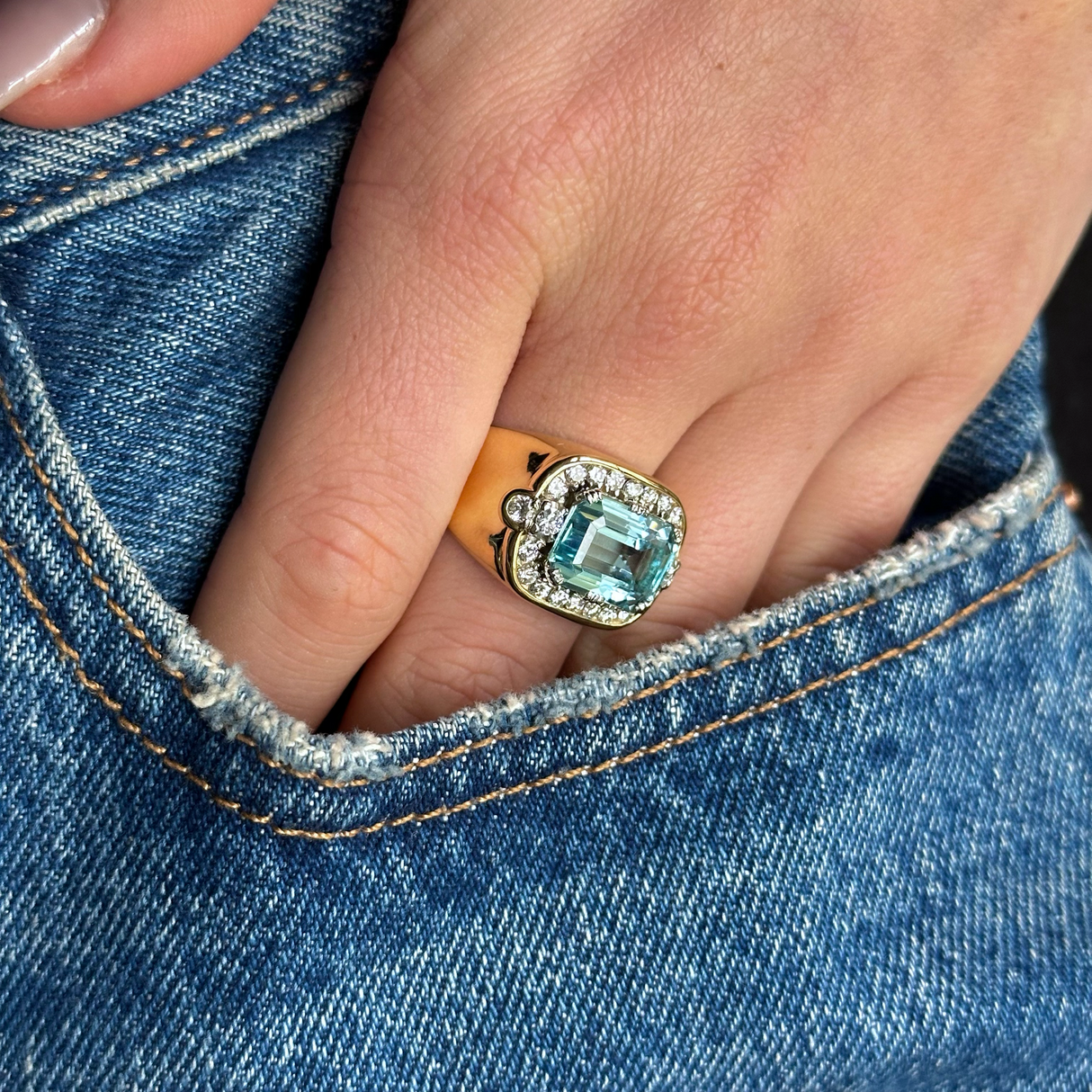 Aquamarine and diamond cocktail ring worn on hand in pocket of jeans.