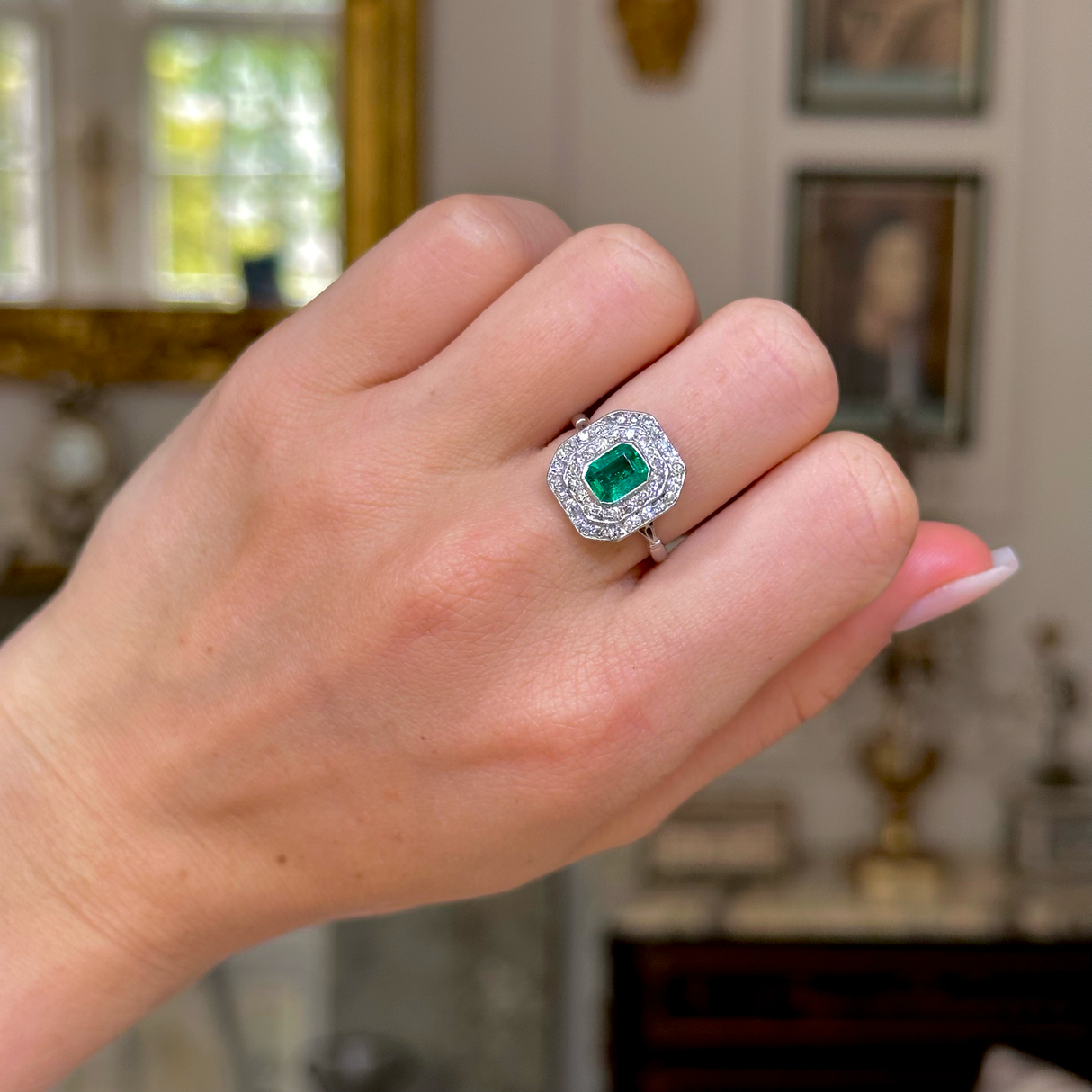 Vintage emerald and diamond cluster ring, worn on hand.