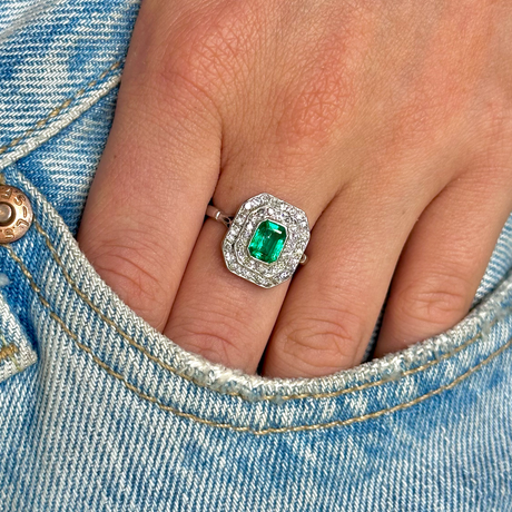 Vintage emerald and diamond cluster ring, worn on hand.