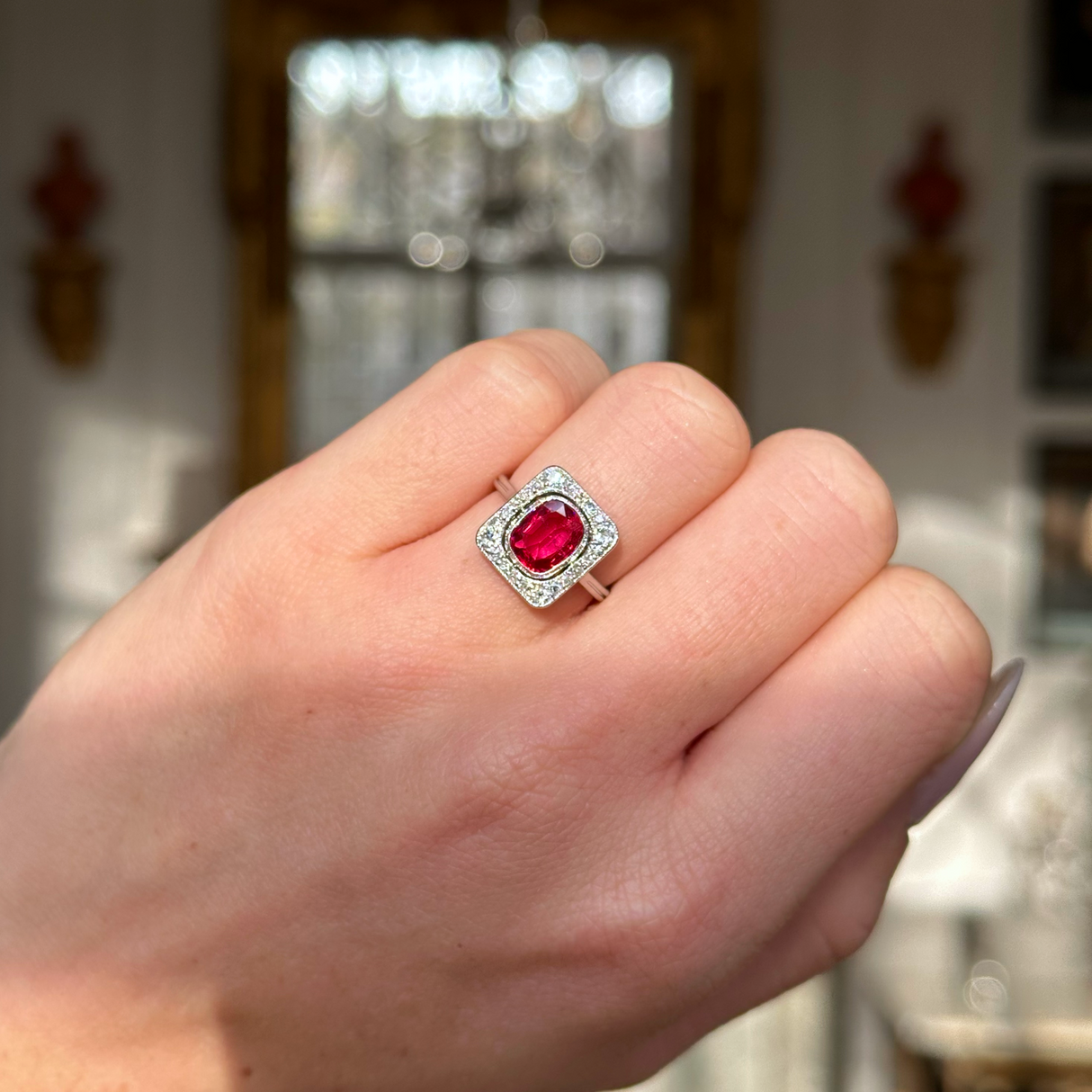 Vintage Art Deco ruby and diamond engagement ring worn on closed hand.