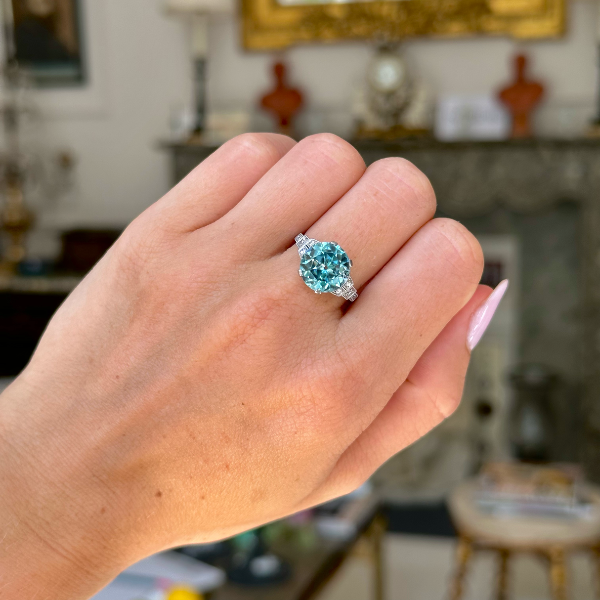 Art deco blue zircon and diamond ring, worn on closed hand, front view. 