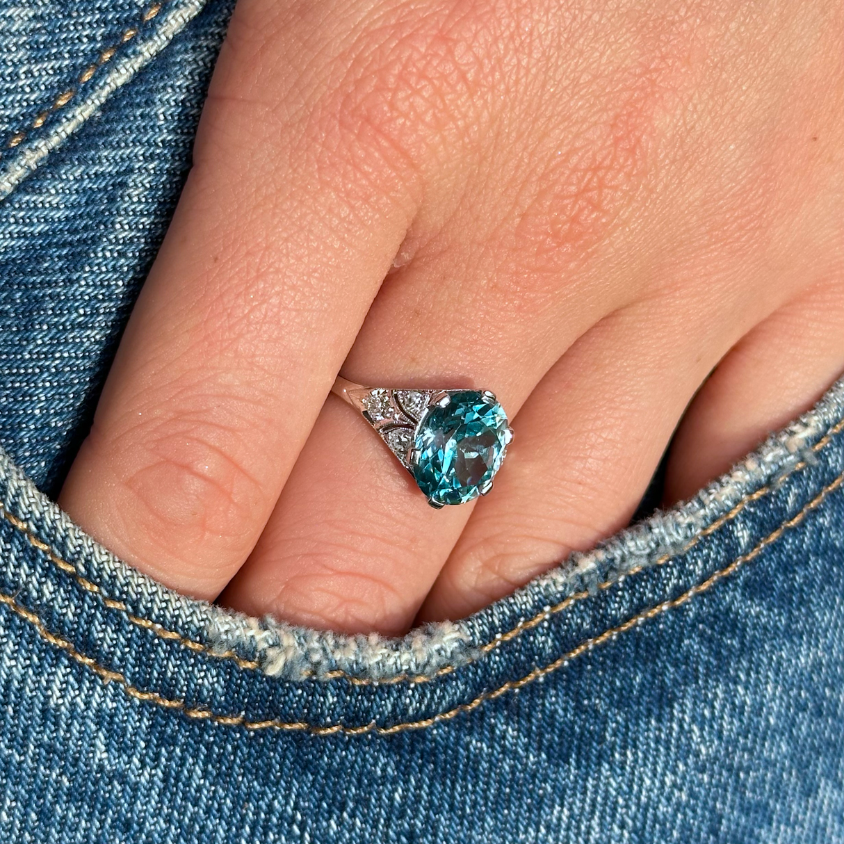 Art deco zircon and diamond ring worn on hand in pocket of jeans.