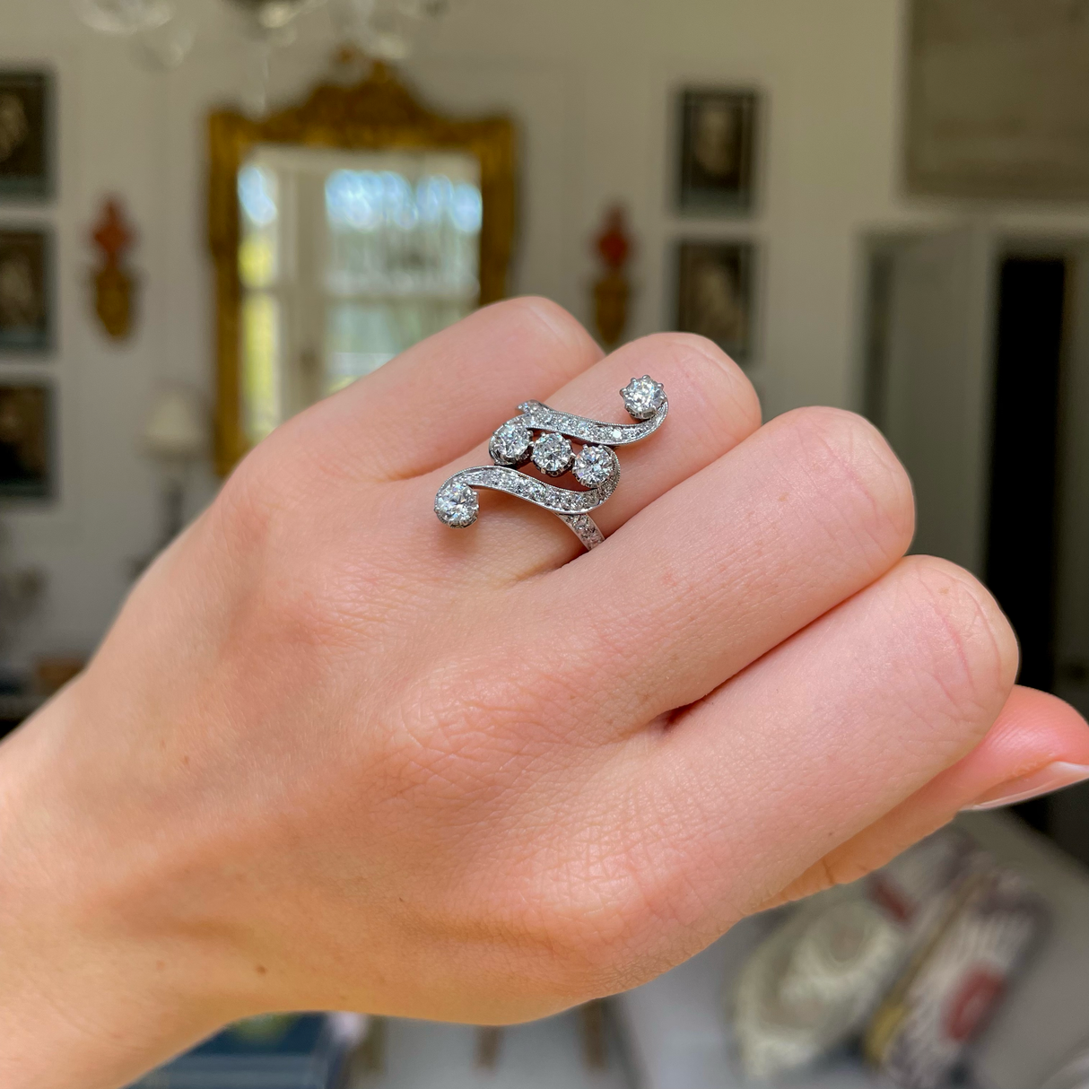Art Nouveau diamond engagement ring, worn on hand.